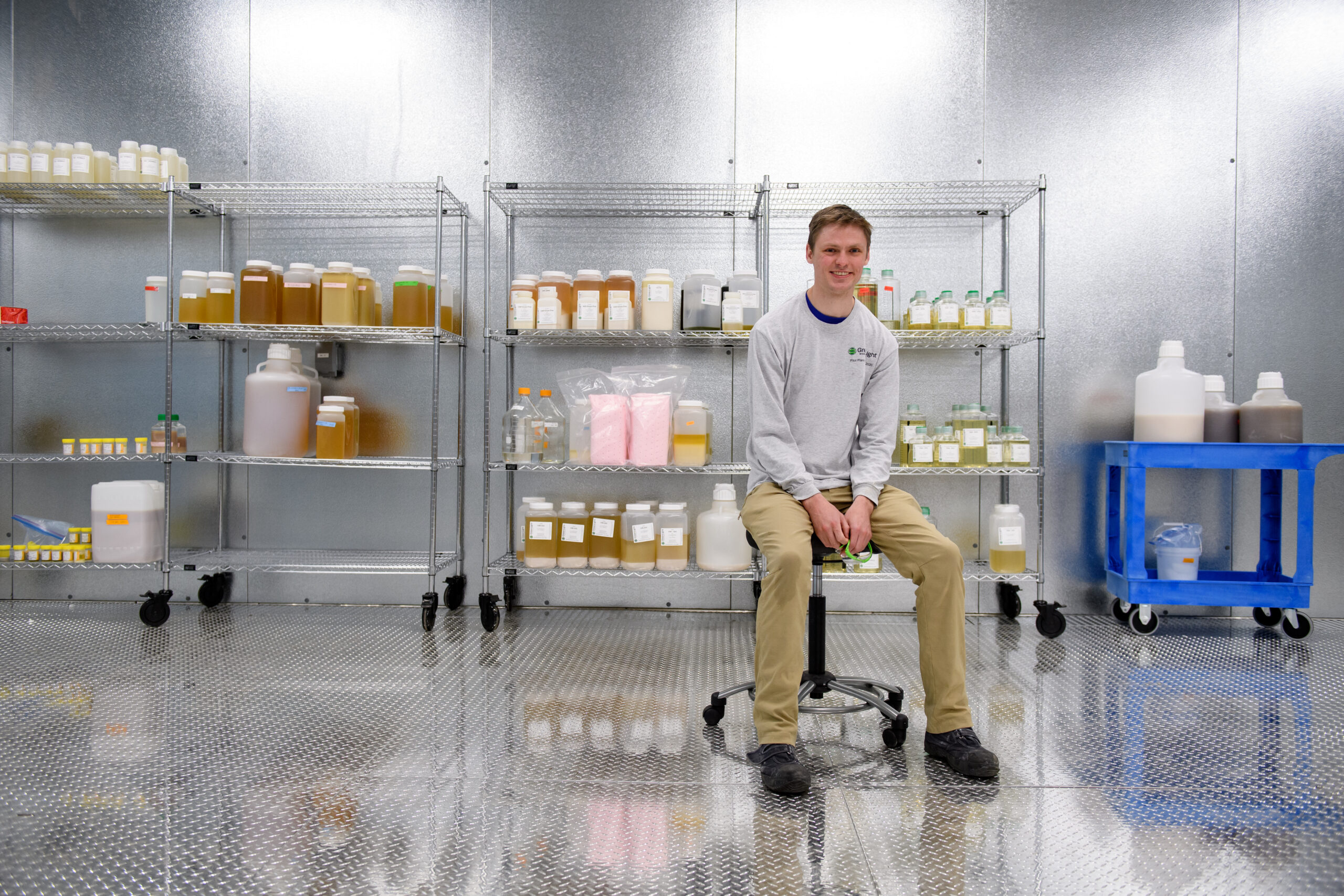 a man sits in front of many big containers of orange liquid